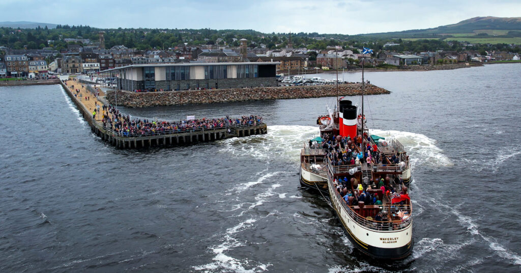 Save the Pier Waverley Visit 2024 - crowds on Helensburgh Pier waving at the Paddle Steamer Waverley. Image courtesy of Destination Helensburgh